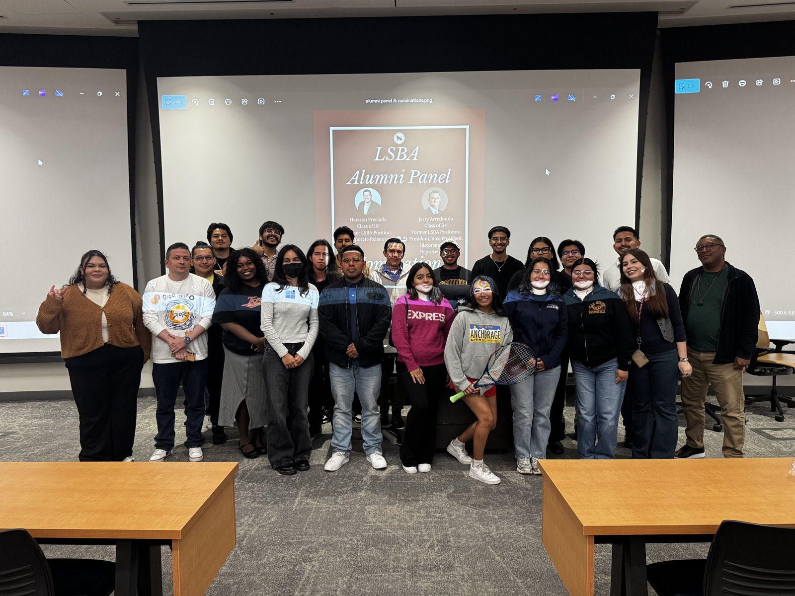 LSBA members and returning alumni standing together in a lecture hall in front of a projected LSBA Alumni Panel slide.