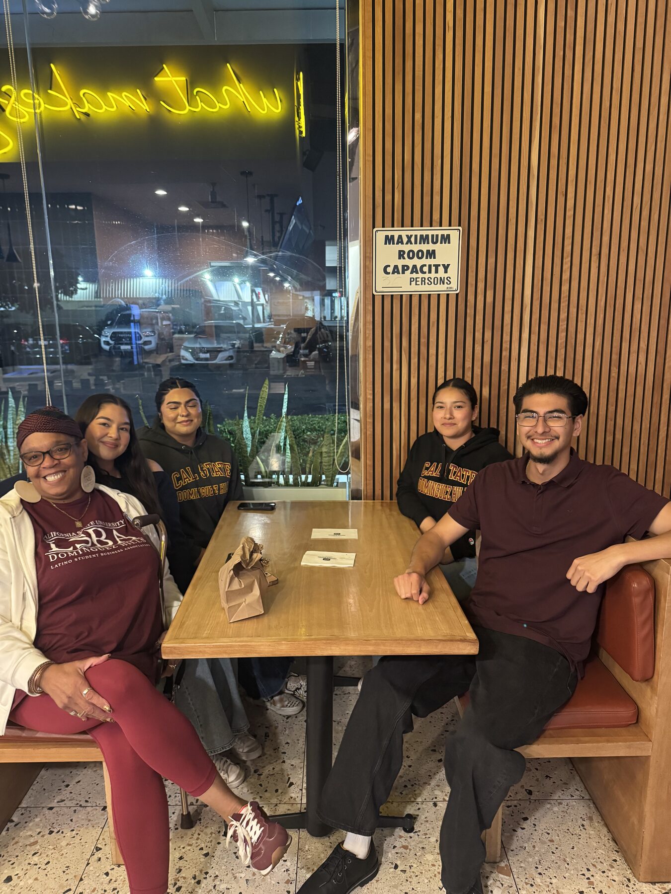 LSBA members and their advisor seated together at a restaurant booth wearing LSBA and Cal State Dominguez Hills apparel.