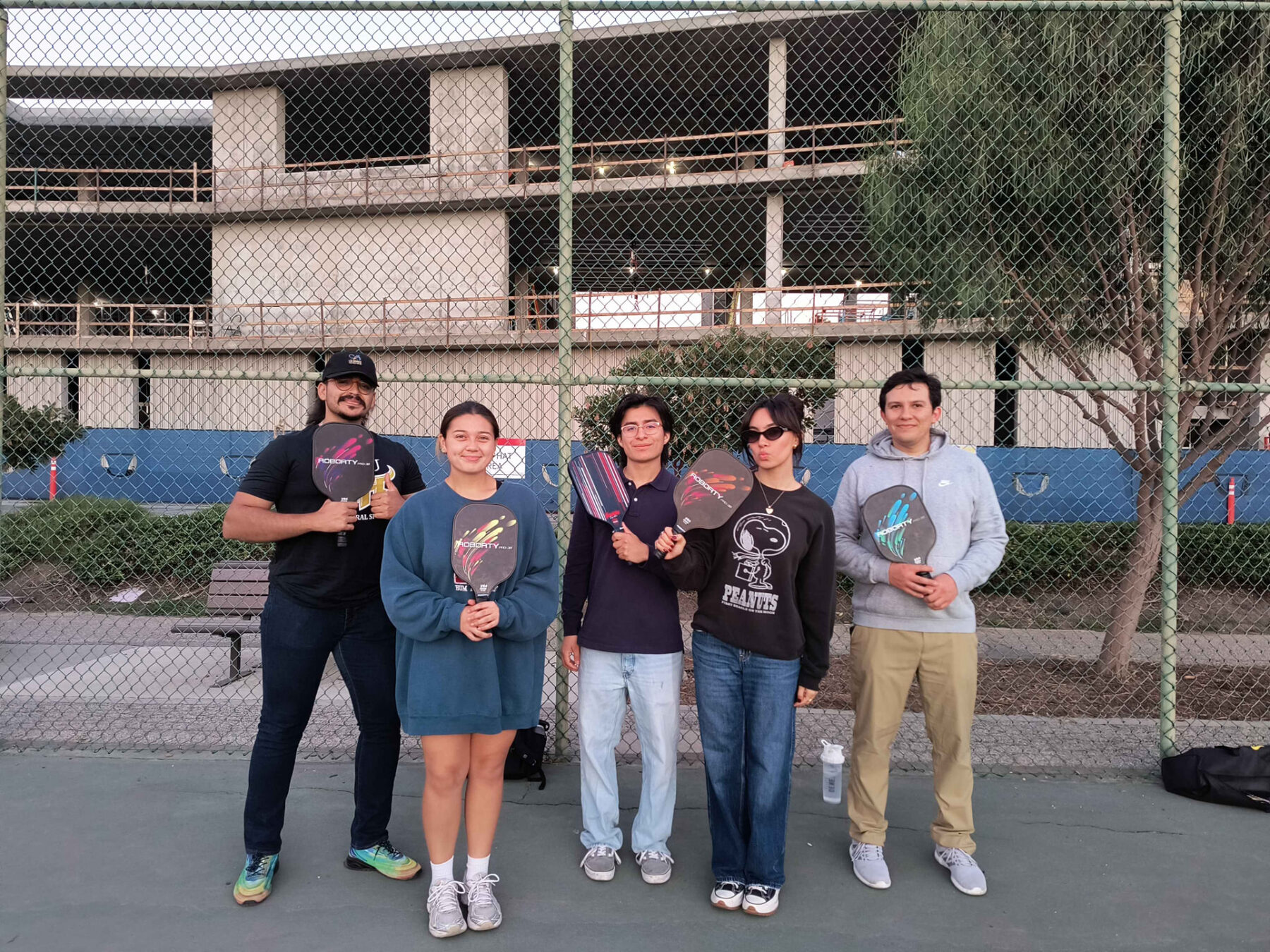 Five LSBA members holding pickleball paddles on the CSUDH courts at an intramural social event.