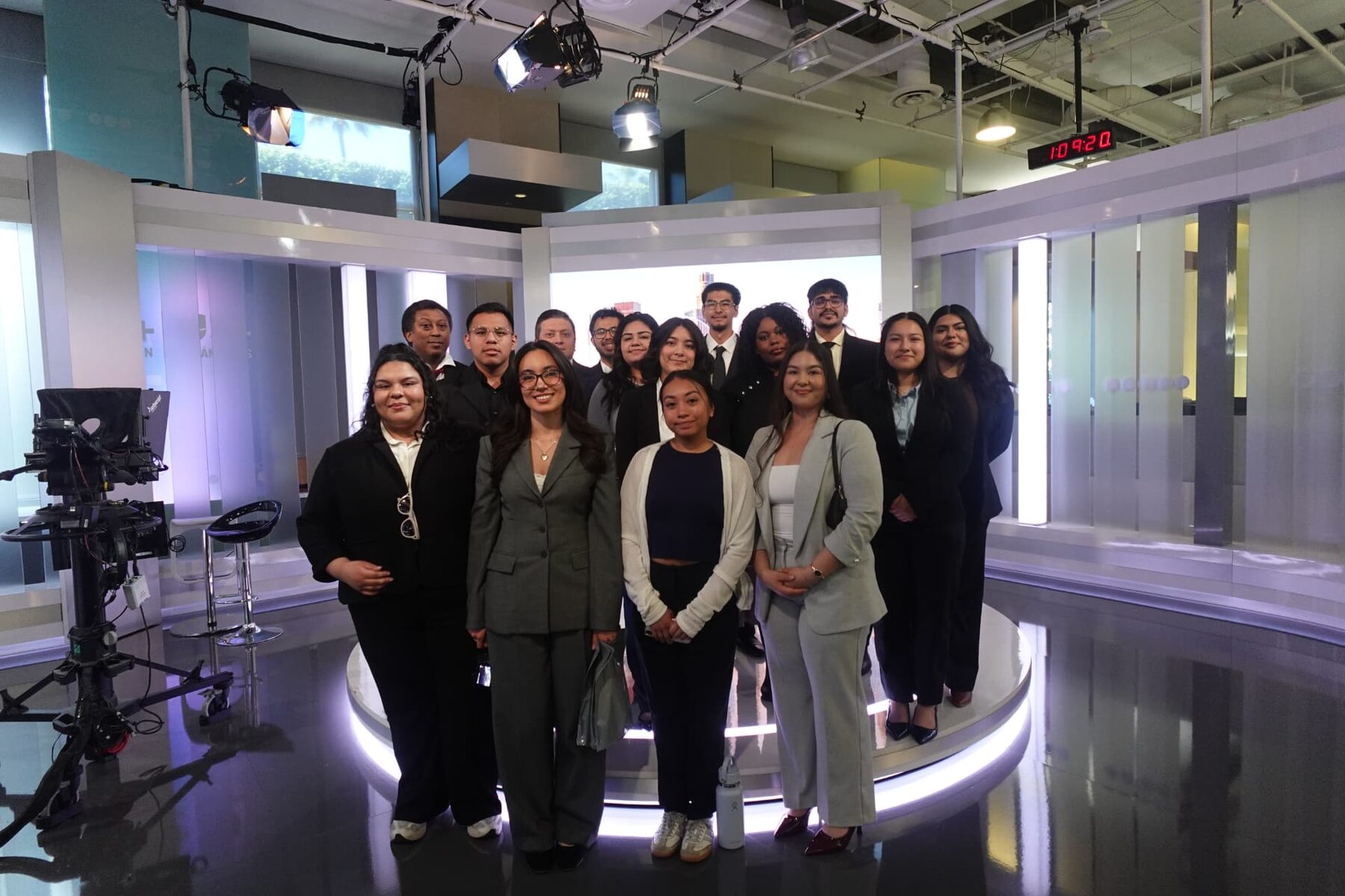 LSBA members in business attire posing on the set of a television news studio during a corporate media tour.
