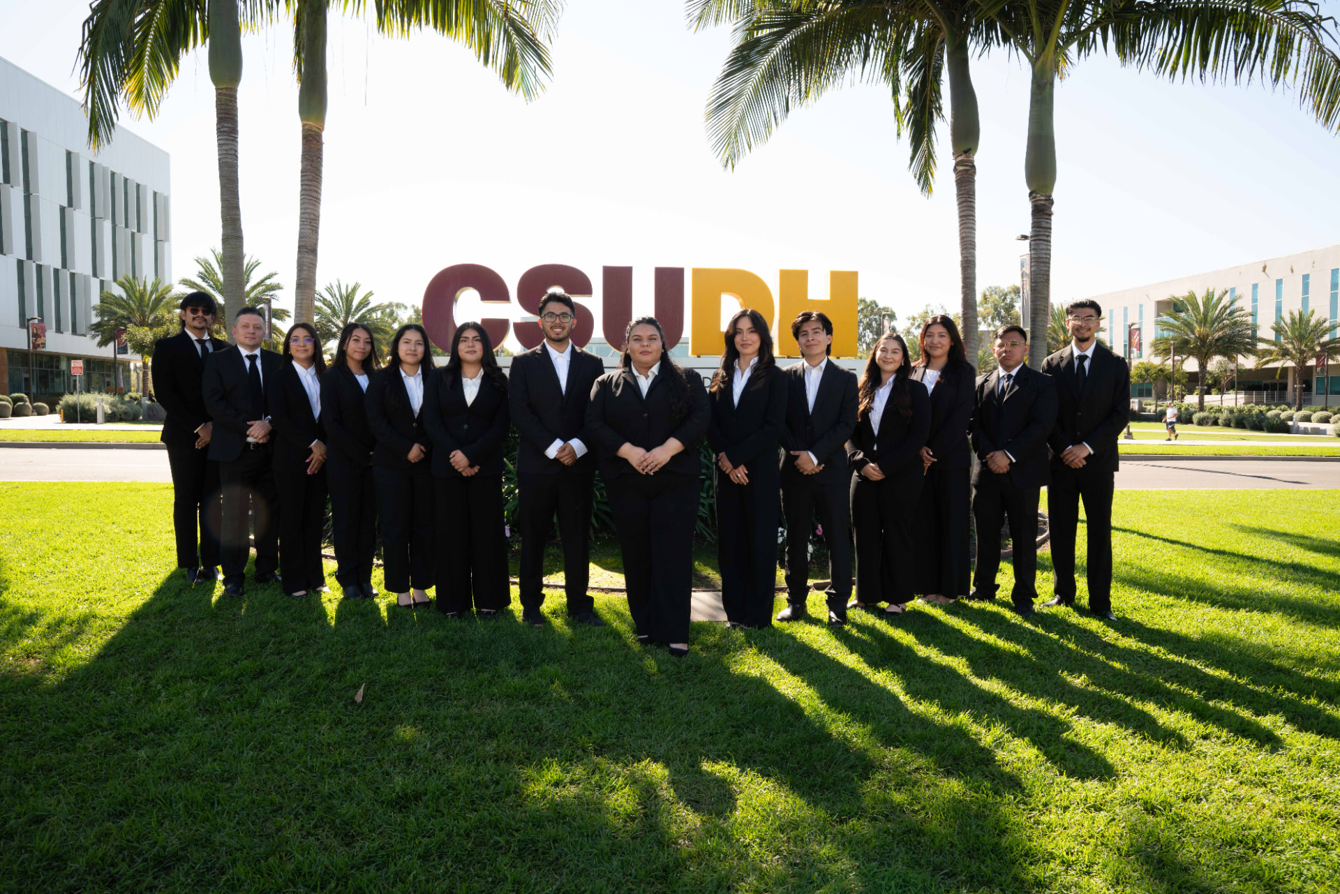 LSBA members standing together in business attire in front of the CSUDH campus sign