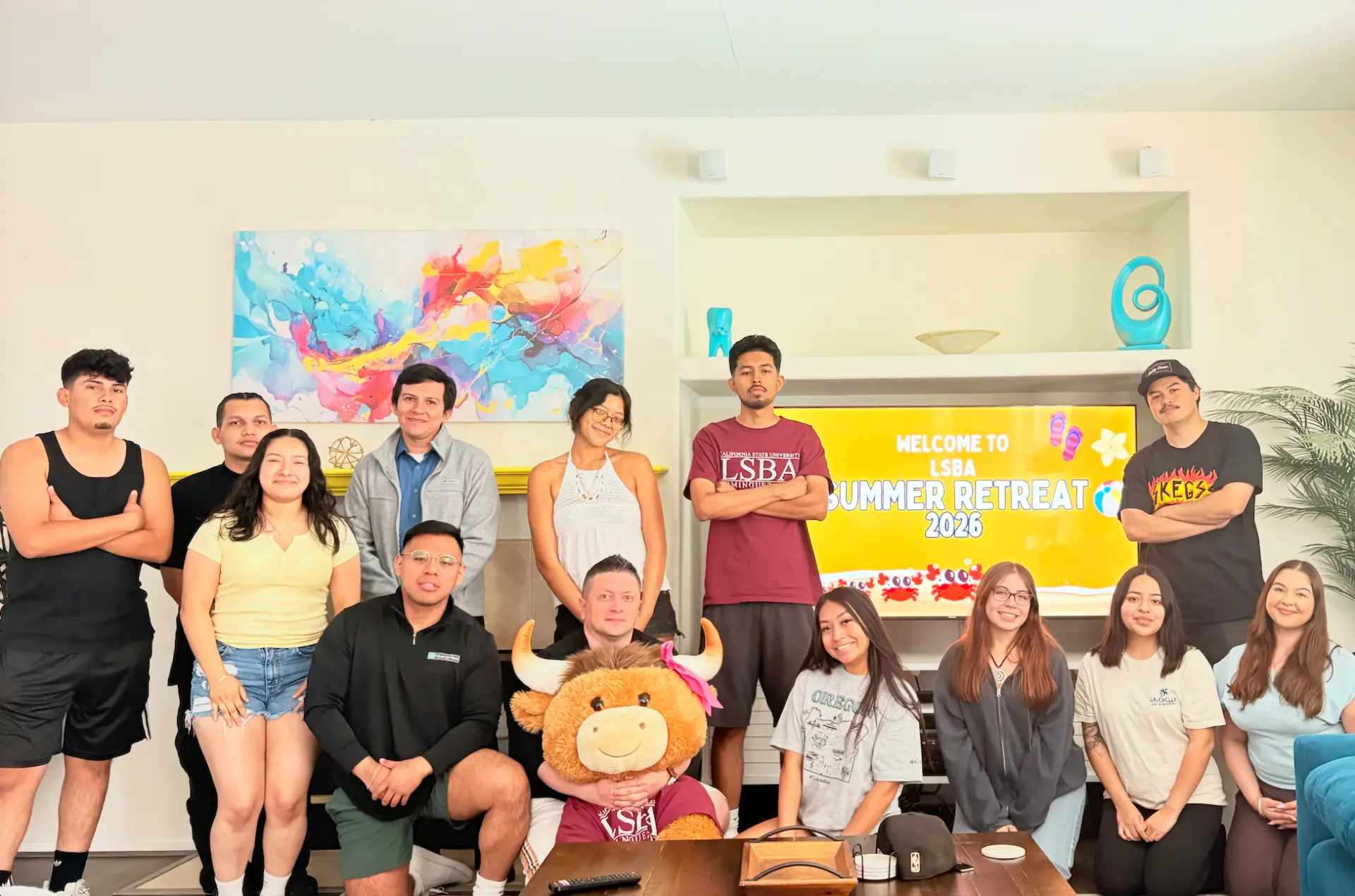 LSBA members posing together in a Coachella-area rental home in front of a screen reading Welcome to LSBA Summer Retreat 2026.